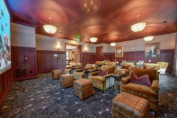 A room with brown leather chairs and tables.